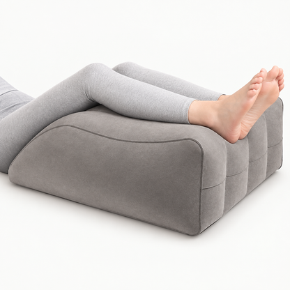 Benen rusten op een grijs ergonomisch beenkussen voor comfortabele ondersteuning en beenelevatie.