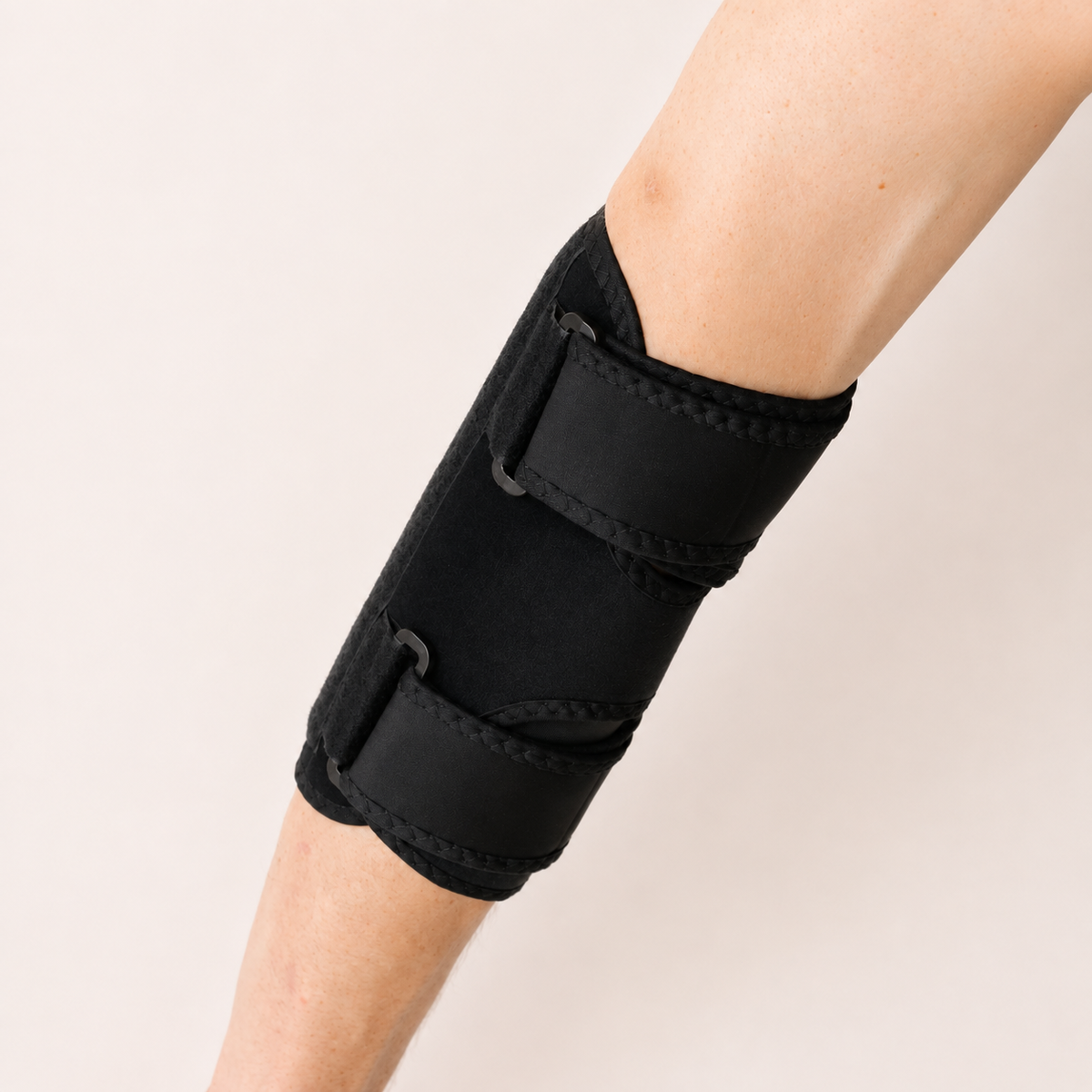 Zijaanzicht van de zwarte elleboogbrace gedragen rond de arm voor ondersteuning en fixatie van de elleboog