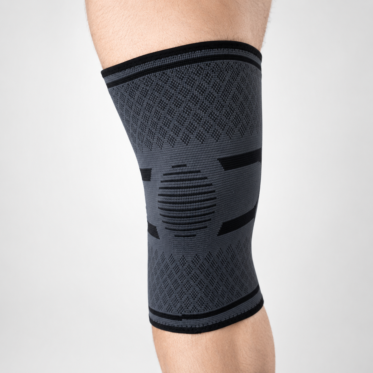 Grijze kniebrace met compressie rondom de knie van voren bekeken