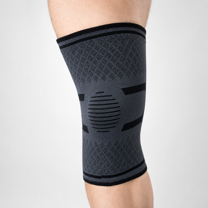 Grijze kniebrace met compressie rondom de knie van voren bekeken