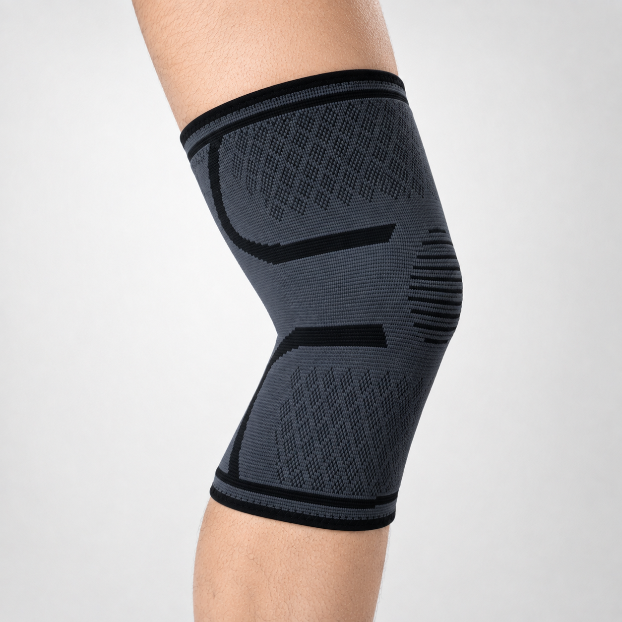 Compressie kniebrace in grijs en zwart gedragen om de knie vanuit de zijkant